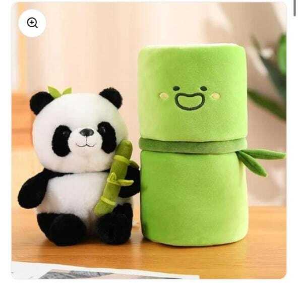 Plush panda toy holding a green bamboo stick next to a green plush toy with a face design on a wooden surface.